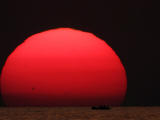extremely zoomed sun at the sunset by the sea