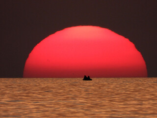 extremely zoomed sun at the sunset by the sea