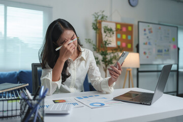 Businesswoman, young Asian woman feeling headache, stress, migraine, financial woman, tired marketing woman Sleepy, overworked while working on a laptop computer in the office.