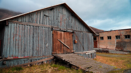 Abandoned wooden structures amidst the mountainous landscape of Pyramiden, Svalbard