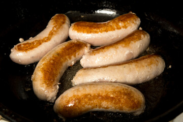  Juicy grilled sausages sizzling in a pan. Perfectly browned, ready to serve. Mouth-watering close-up of traditional meat sausages. 