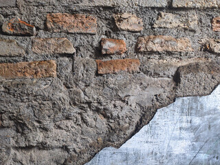 The fragments of an old brick wall have a reddish-orange texture, with gray cement plaster that has peeled off in the lower right corner.