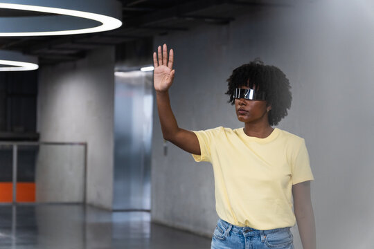 Young trendy woman wearing futuristic visor interacting with metaverse