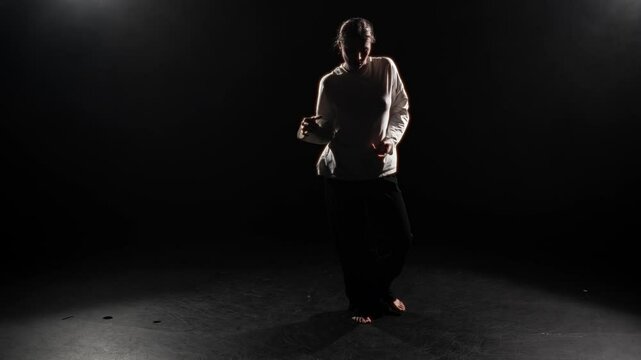 Freestyle dance performance in school of arts, woman dancing on stage alone. Hobby and arts, young female dancer moving actively in darkness, silhouette, enjoy modern music, be in motion, girl dancer