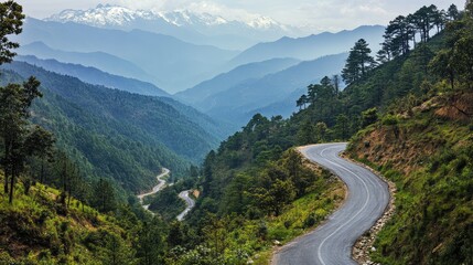 A twisting road cutting through a dense forest on a mountainside, the sharp curves revealing glimpses of distant snow-capped peaks
