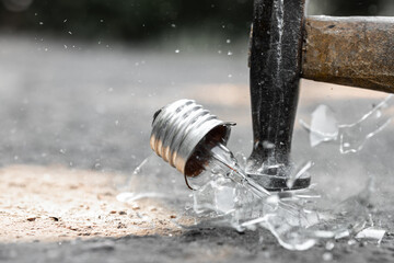 Closeup of hammer tool destroying electric light bulb, Hammer striking an incandescent lamp,...