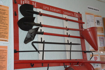 Fire safety station with tools on a red and white rack labeled in Russian. Includes shovels, fire...