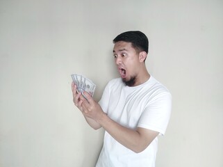 Adult Asian man showing excited face expression when looking to US dollar money that he hold