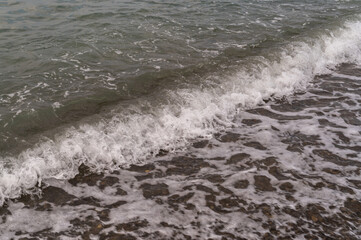 Fototapeta premium Sea waves on the pebble beach. Blue sea surface with waves. Abstract background of water flow in ocean, sea, river, lake. Seascape wallpaper.