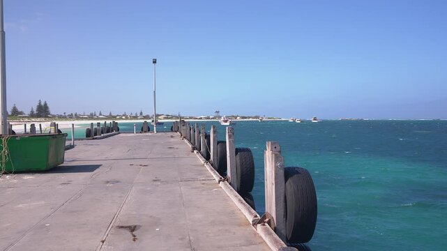 A slow walk forward along Lancelin jetty at mid-morning time with boats off the beach.