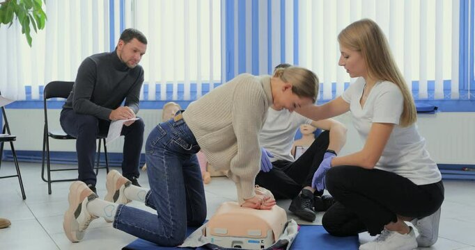 Woman demonstrating CPR on mannequin in first aid class.