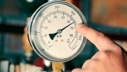Close-up of air pressure gauge with finger pointing at 70 psi. A close-up shot of an air pressure...