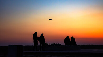 People watching a plane take off at sunset