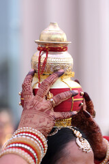 Obraz premium Traditional Indian kalash adorned with red and gold decorations, symbolizing prosperity and purity in sacred rituals.