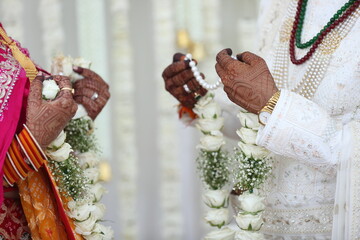 A heartfelt exchange of garlands, marking the beginning of lifelong journey together. Delicate garlands in hand, symbolizing a bond that transcends words. An intimate wedding ritual filled with love.