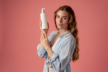 studio beauty shoot on pink background long-haired girl sitting posing in underwear in blue shirt...