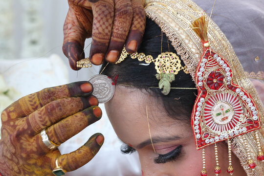 Indian wedding ritual where sindoor (vermilion) is being applied to the bride's hair parting, symbolizing the sacred bond of marriage.	