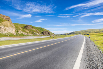 Fototapeta premium Country road and green grassland with mountain natural scenery. Road trip.