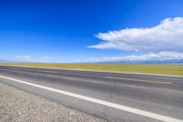 Country road and green grassland nature landscape under blue sky. Road trip.