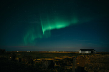 Dancing aurora borealis above Icelanding farm on the night sky