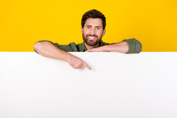 Photo of nice young man indicate finger empty space wear shirt isolated on yellow color background