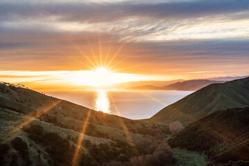 Beautiful sunset vista over ocean and green mountains