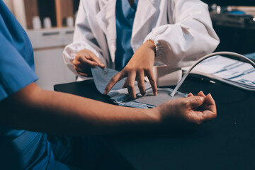 Fototapeta premium A doctor taking a patient's blood pressure. The patient's arm is equipped with a blood pressure cuff, and the doctor is using a blood pressure monitor.