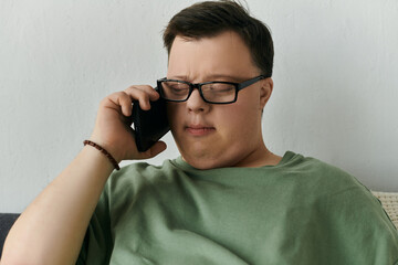 man with Down syndrome engages in a thoughtful phone call while seated comfortably at home.