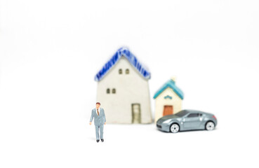 Miniature business man with car and house model on white background, life goal and archievement
