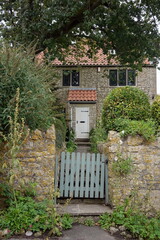 Wooden gate at the garden entrance of a beautiful old cottage house on a street in an English town