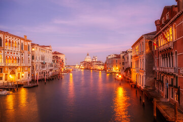 Naklejka premium A serene evening view of Basilica di Santa Maria della Salute by the Grand Canal in Venice, showcasing the tranquil waters reflecting the stunning architecture at sunset. Italy