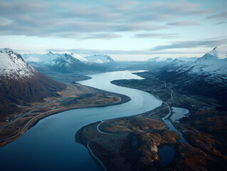 Serpentine river winding through snow-covered mountains and valleys, viewed from above in a remote winter landscape
