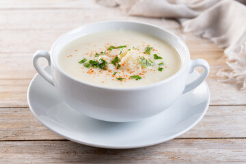 Cauliflower soup in bowl on wooden table