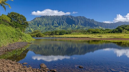 A serene mountain reflection in a still pond with lush greenery in the foreground.