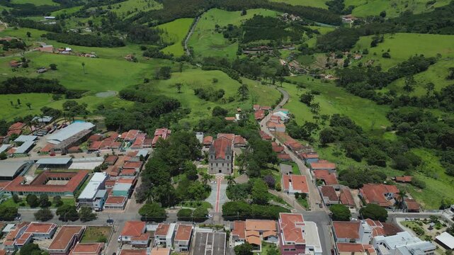 bird eye view looking down to a church in the middle of a small town surrounded by green hills - Bueno Brandao, a touristic city in south of Minas Gerais, Brazil