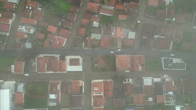 aerial view going up of a real state area - Red roof' houses and linear bloc streets disappearing into the foggy - Bueno Brandao, Minas Gerais, Brazil