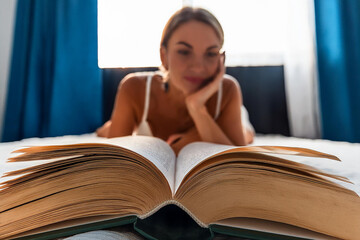 vista di una donna in bichini sdraiata sul letto mentre legge un libro.