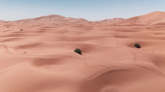 Drone shot over big dunes in morocco desert on sahara merzouga with cars