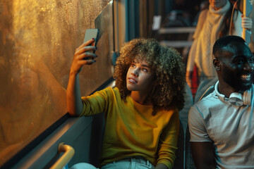 Fototapeta premium Young woman taking a selfie on a bus at night