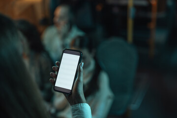 Person holding smartphone with blank screen in dimly lit setting