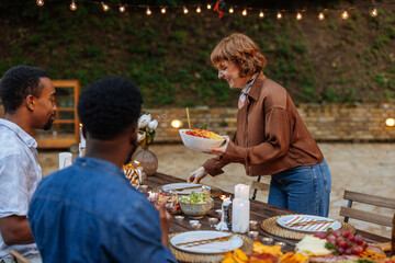 Woman placing a bowl pasta with sauce on a wooden table