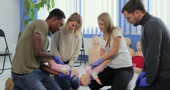 Group of multiethnic people during the first aid training with instructor showing on manikin how to do artificial respiration for the baby.