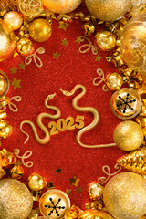 golden Snakes figurines and festive new year decoration with 2025 numbers on red background....