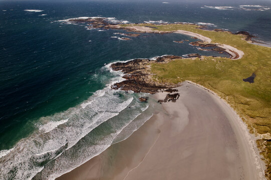 Aerial view of breaking waves at a sandy beach along the coastline, Isle of Tiree, United Kingdom.
