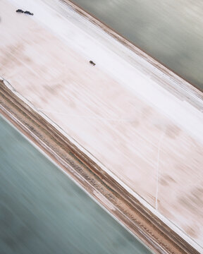 Aerial view of serene salt marshes and a winding road amidst expansive natural beauty, Useless Loop, Western Australia.