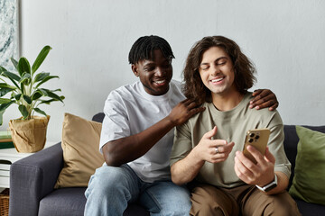 A loving couple shares laughter while looking at their phone in their comfortable home.