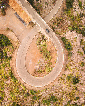 Aerial view of winding road through rocky terrain and lush vegetation, Sa Calobra and Nus de Sa Corbata, Escorca, Spain.