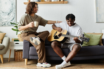 A happy couple share a tender moment while one strums a guitar and the other sips coffee.