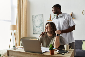 Two partners share a loving moment while working together in their bright home office.