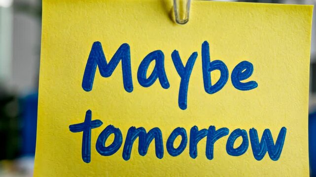 Yellow sticky note with Maybe Tomorrow message clipped to a string, symbolizing procrastination and motivation